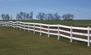 White fence along an open field, showing a physical feature that can help clarify an older property plat through survey mapping